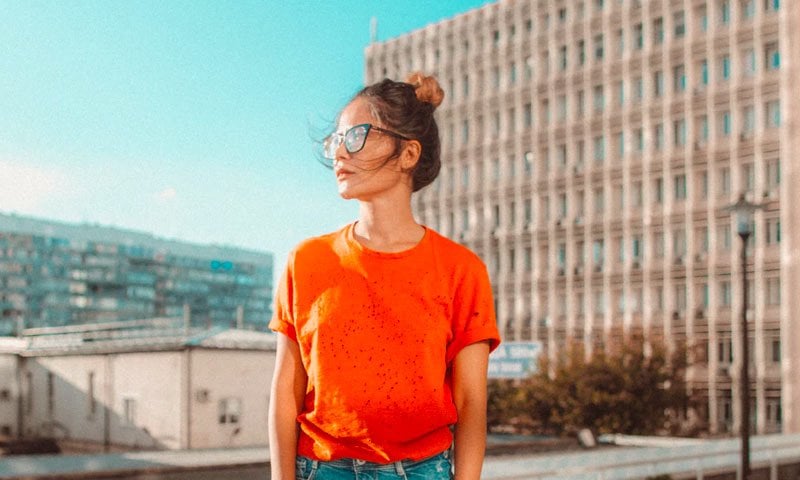 Young woman wearing bright orange t-shirt outdoors, representing Nielseun customer testimonial